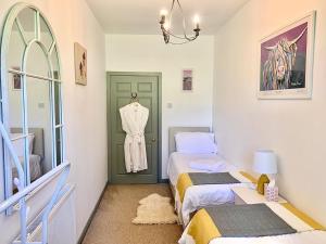 a bedroom with two beds and a dress hanging on a door at The Stables in Meikle Wartle