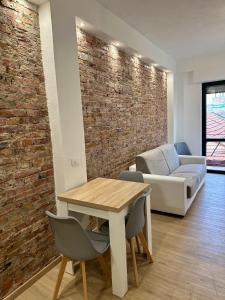 sala de estar con pared de ladrillo, mesa y sillas en F&F Appartments, en Iglesias