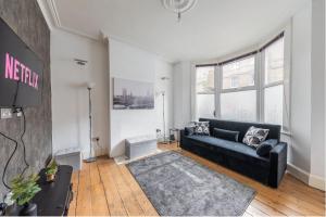 a living room with a black couch and a tv at Charming 1 Bed Flat w Courtyard in Central London in London