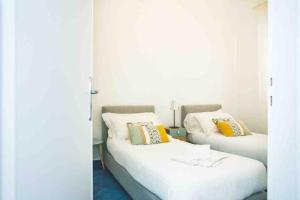 トラッペートにある3 bedrooms apartement at Piano di Trappeto 1 m away from the beach with sea view furnished terrace and wifiの白い壁の客室で、ベッド2台、黄色の枕が備わります。