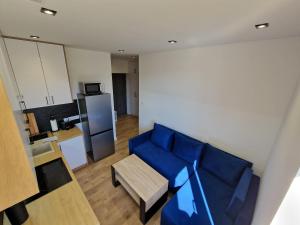 ein Wohnzimmer mit einem blauen Sofa und einem Tisch in der Unterkunft YourSecondFlat Sobieski Apartment in Dębica