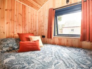 a bed in a wooden room with a window at Dunfell Shepherd's Hut in Dufton