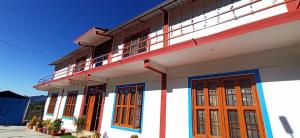 ein weißes Gebäude mit orangefarbenen Türen und einem Balkon in der Unterkunft Villotale Khadait SH in Badīyārgaon
