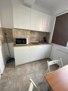 a small kitchen with white cabinets and a microwave at Relax Studio Militari Residence Sector 6 in Roşu
