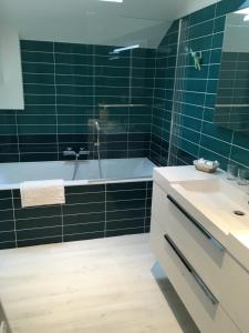 y baño con azulejos verdes, bañera y lavamanos. en Chez Lilette en La Baule