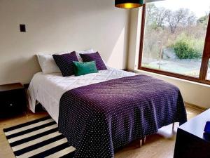 a bedroom with a bed with a purple blanket and a window at Departamento frente al lago Villarrica in Villarrica