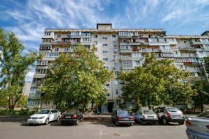 a large building with cars parked in a parking lot at Kvartirkoff na Polku Azov 32b in Kyiv