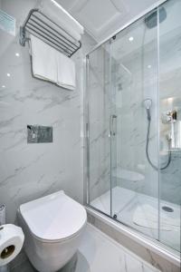 a white bathroom with a shower and a toilet at Queens Park Premier London Hyde Park in London