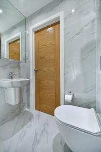 a white bathroom with a toilet and a sink at Queens Park Premier London Hyde Park in London