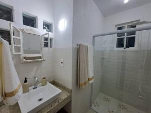 a white bathroom with a sink and a shower at Orobó Kaá - entre a floresta e a vida no campo in Monteiro Lobato