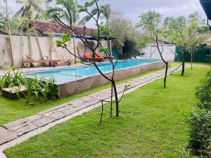 una piscina en un patio con árboles en el césped en Oasis Ayurveda resort en Wadduwa
