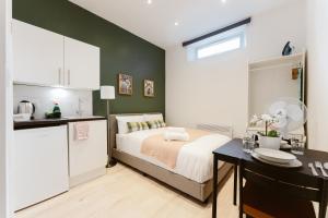 um quarto com uma cama e uma cozinha com uma mesa em The Finsbury Park Star Apartments em Londres