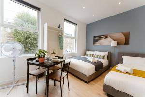 a bedroom with two beds and a desk and a table at The Finsbury Park Star Apartments in London