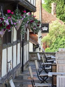 a group of chairs sitting outside of a building with flowers at The Crown Inn in Chiddingfold