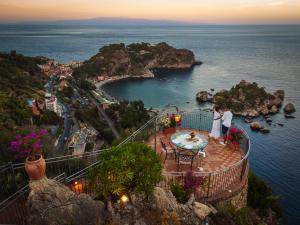 a couple standing on a balcony overlooking the ocean at Grand Hotel San Pietro in Taormina