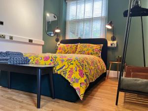 a bedroom with a bed with a colorful bedspread and a table at The Boot Room Ground Floor Studio Apartment in Burnham-on-Crouch
