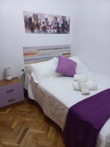 a bedroom with a bed with purple and white pillows at CASA ESQUILAS in Avila