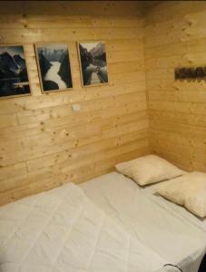 a bed in a wooden room with pictures on the wall at Chalet 77 proche S Besse in Égliseneuve-dʼEntraigues