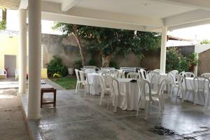 grupa białych krzeseł i stołów w pawilonie w obiekcie João Pessoa e Cabedelo CASA CAMBOINHA w mieście Cabedelo