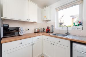 a kitchen with white cabinets and a sink and a window at Modern Living in a 2BR near Milton Keynes in Milton Keynes