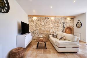 un soggiorno con divano bianco e TV di La Mottinière a Saint-Hilaire-du-Rosier