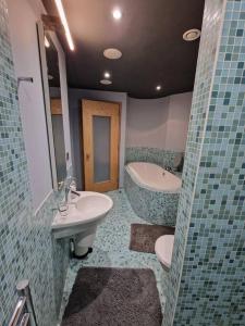 Luxury central Newcastle apartment, sleeps 8 في نيوكاسل أبون تاين: حمام مع حوض وحوض استحمام ومرحاض