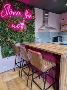 een keuken met een bar met stoelen en een neonbord bij Luxury central Newcastle apartment, sleeps 8 in Newcastle upon Tyne
