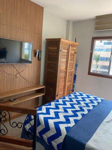 a bedroom with a bed and a dresser and a television at Suíte Itaipu Mar in Vila Velha