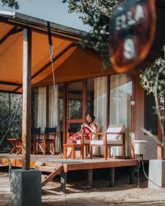 une femme assise sur une terrasse couverte d'une maison dans l'établissement Wild Trails Yala by Suri, à Yala