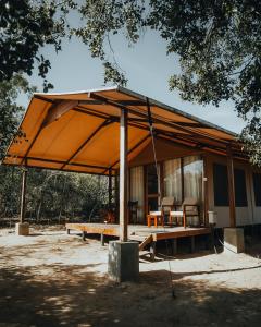 a house with a large roof with a table and chairs at Wild Trails Yala by Suri in Yala