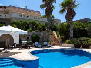 ein Pool vor einem Haus mit Palmen in der Unterkunft Villa Palma - Sunset Sea Views with Pool, Jacuzzi, Sauna and Games Room in Mellieħa