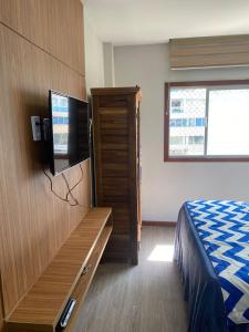 a hotel room with a bed and a tv at Suíte Itaipu Mar in Vila Velha