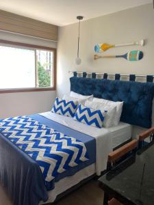 Schlafzimmer mit einem Bett mit einer blauen und weißen Bettdecke in der Unterkunft Suíte Itaipu Mar in Vila Velha