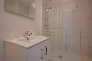 a white bathroom with a sink and a shower at Hôtel Le Nautic in Arcachon