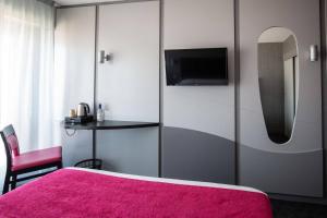 a bedroom with a pink bed and a table at Hôtel Le Nautic in Arcachon
