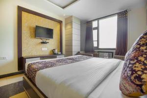 1 dormitorio con 1 cama grande y TV en la pared en VK Hotels & Resorts en Amritsar