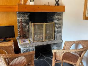 a stone fireplace with two chairs and a television at Appartement proche des pistes avec terrasse sud - FR-1-411-687 in Les Allues