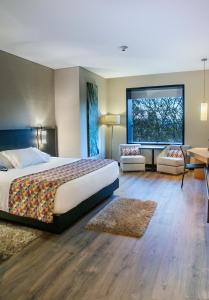 a bedroom with a large bed and a large window at Cité Hotel in Bogotá