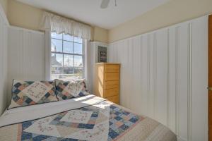 a bedroom with a bed with a quilt and a window at Cozy Hampton Vacation Rental, Walk to Beach! in Hampton