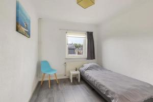 um pequeno quarto com uma cama e uma cadeira azul em Apeldoorn- ruime eengezinswoning met 5 slaapkamers em Apeldoorn