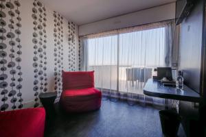 a room with a red chair and a desk and a window at Hôtel Le Nautic in Arcachon