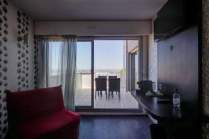 d'un salon avec un canapé rouge et un balcon. dans l'établissement Hôtel Le Nautic, à Arcachon