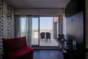 a living room with a red couch and a balcony at Hôtel Le Nautic in Arcachon