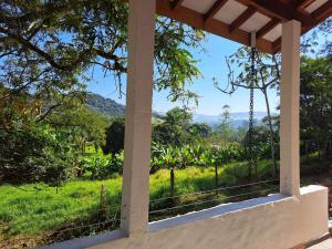 a view from the porch of a house with a view of a field at Orobó Kaá - entre a floresta e a vida no campo in Monteiro Lobato