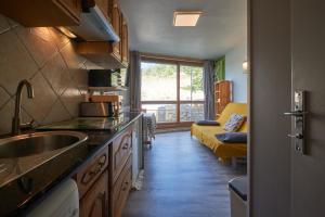 a kitchen with a sink and a living room with a couch at Studio Villard De Lans in Villard-de-Lans