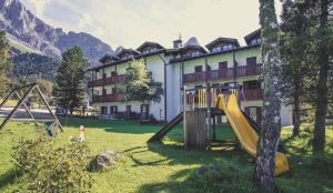 un parco giochi di fronte a un grande edificio di Appartamento con terrazza di mq 40 con vista Pale di San Martino a San Martino di Castrozza