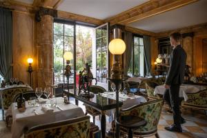 Un homme est debout dans un restaurant avec des tables dans l'établissement La Réserve Paris Hotel & Spa, à Paris