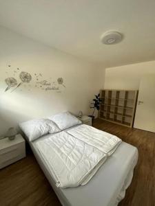 - une chambre avec un lit blanc et des fleurs sur le mur dans l'établissement Ferienwohnung in Arnoldstein, à Arnoldstein