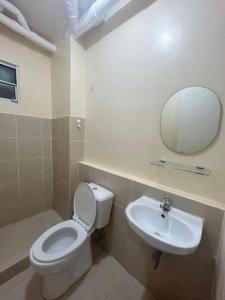 een badkamer met een toilet, een wastafel en een spiegel bij BRIA FLATS LAS PINAS in Manilla