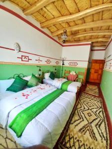 1 dormitorio con 1 cama grande con sábanas verdes y blancas en Maison d'Hôte Argana, en Aït Idaïr